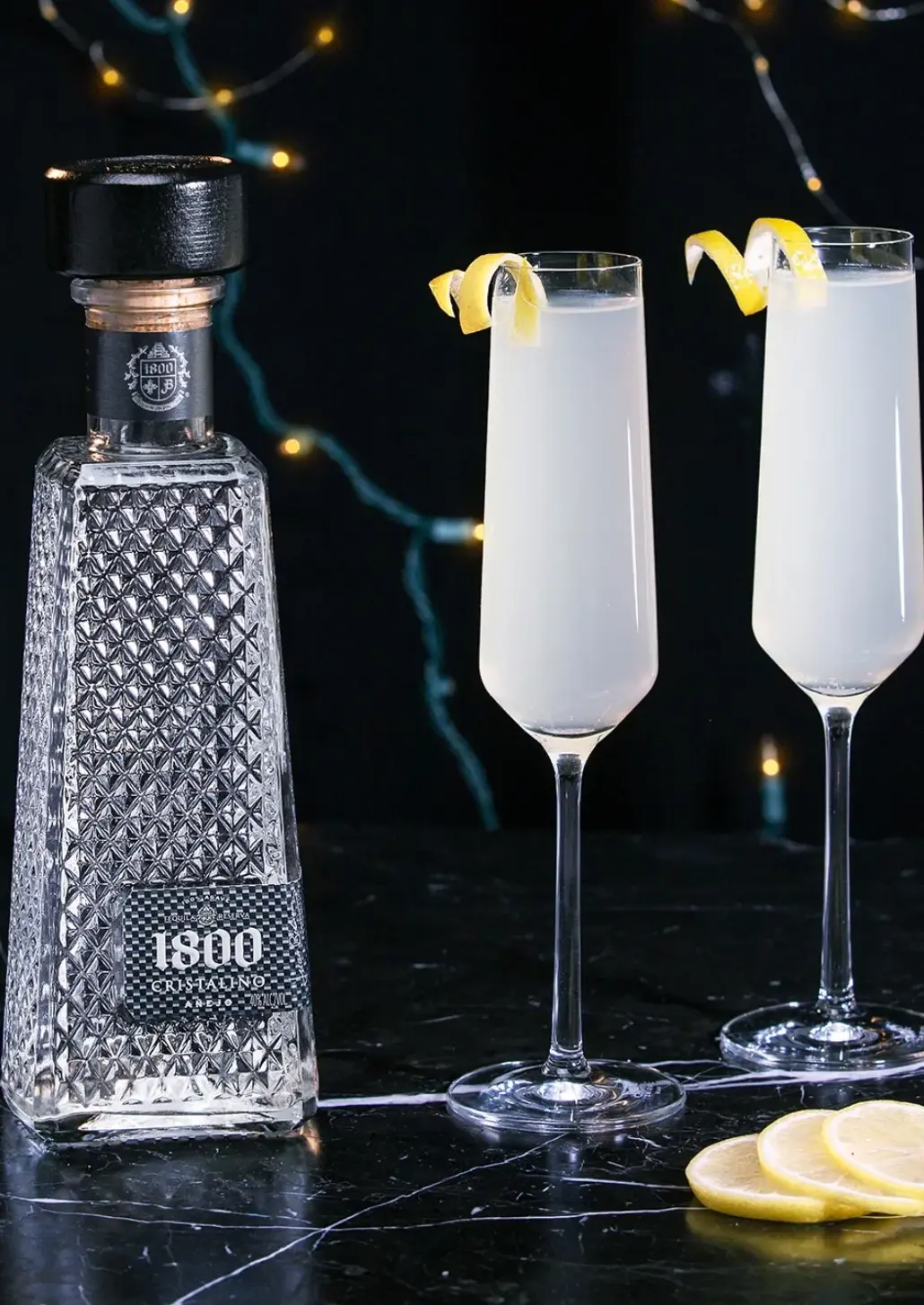 bottle of 1800 cristalino tequila and 2 champagne flutes of 75 jalisco cocktail